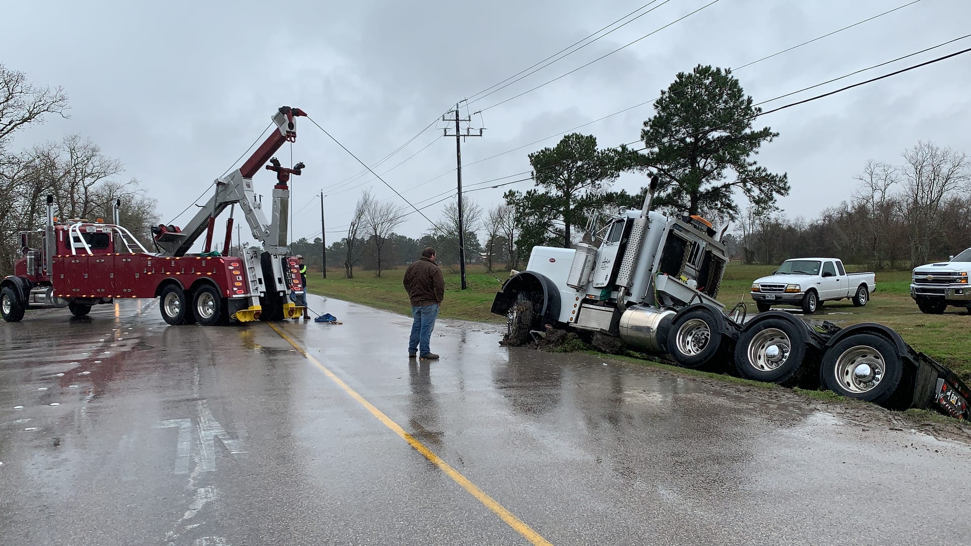 Heavy rotator recovering a Peterbilt semi off a rainy Texas roadside